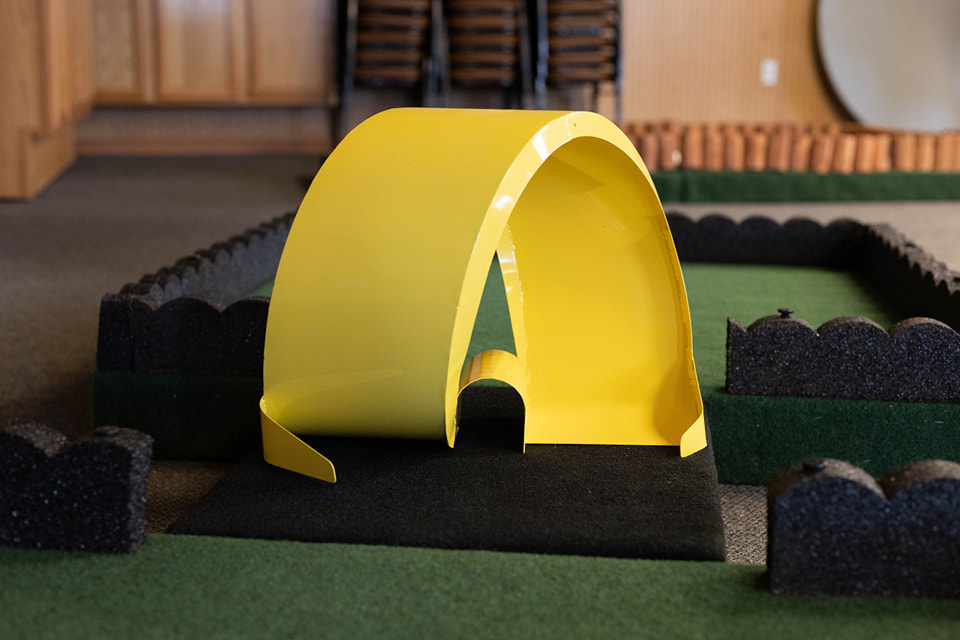 Close-up of a custom yellow tunnel obstacle on a Steel City mini golf hole