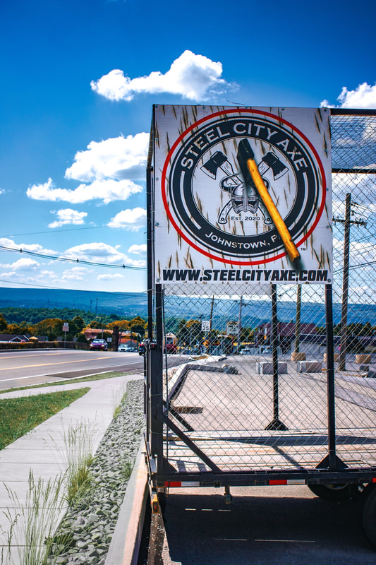 Steel City Axe mobile trailer signage against a blue Pennsylvania sky