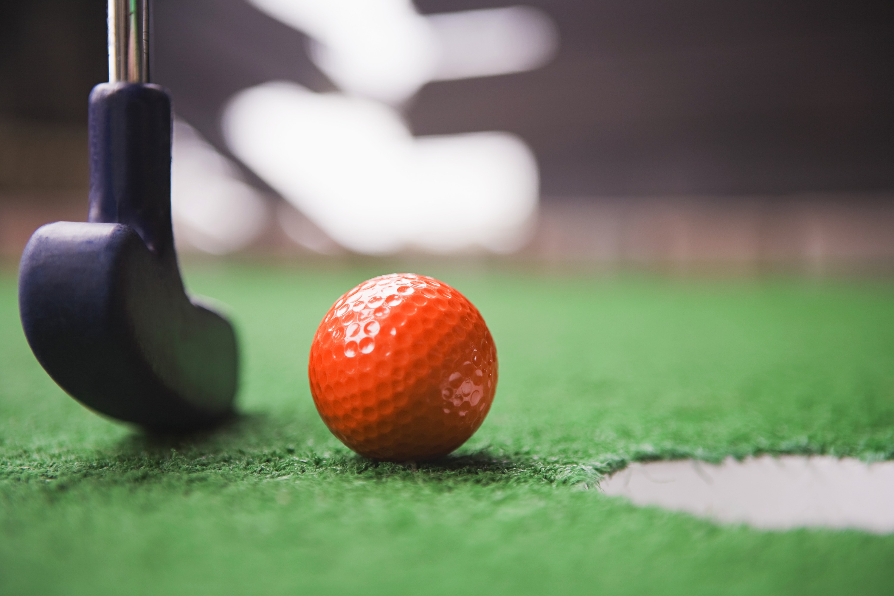 Close-up of a putter and orange ball on a Steel City mobile mini golf hole